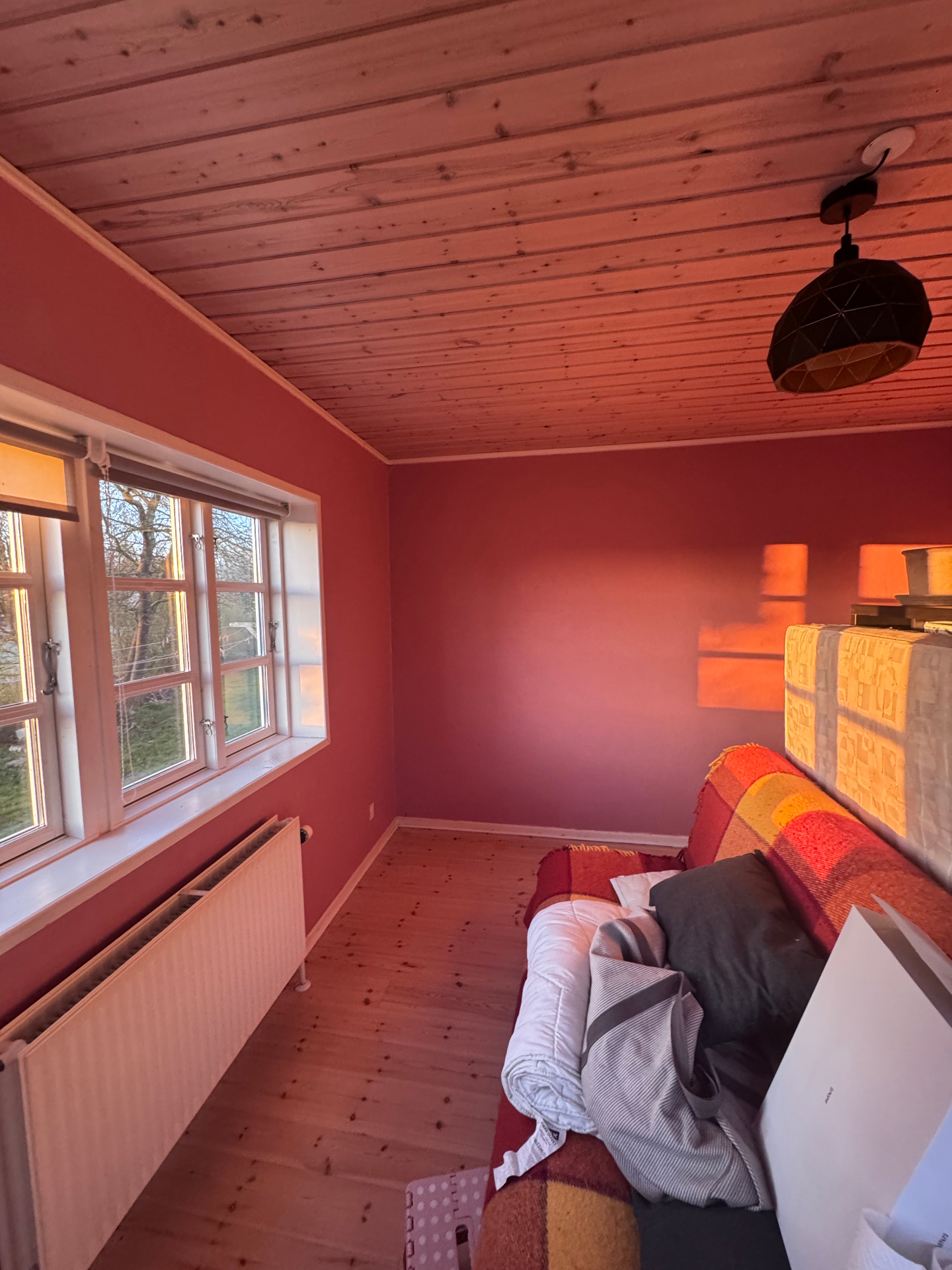 Færdigmaltet stue med rosenrøde vægge og varmt aftenlys fra vinduet