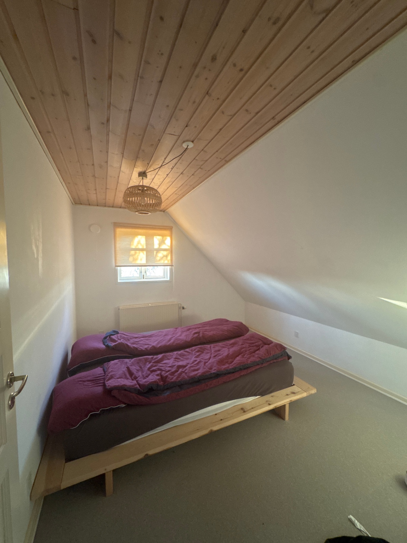 Værelse før renovering med lyst værelse, seng og neutrale vægge